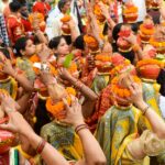 Colorful and festive gathering of women in traditional attire, carrying decorated vases.
