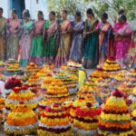Vibrant display of women celebrating the Bathukamma festival with colorful flower arrangements in India.